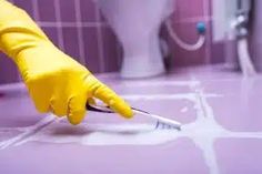 a person in yellow gloves cleaning a bathroom floor