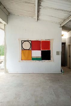 an empty room with white walls and paintings hanging on the wall in front of it