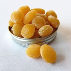 a tin filled with yellow candies on top of a white cloth covered tablecloth