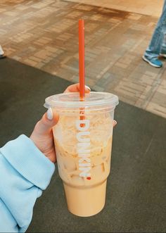 a person holding up a plastic cup with a straw in it