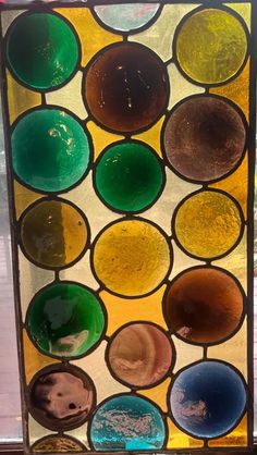 a stained glass window with many different colors and shapes on it's side, in front of a window sill