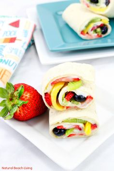 two wraps with fruit on them are sitting next to a strawberry