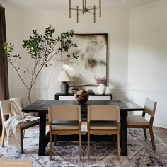 a dining room table with chairs and a painting on the wall in the back ground