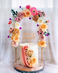 a wedding cake decorated with flowers and the word happy bride on top is sitting on a wooden stand