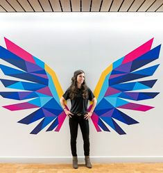 a woman standing in front of a colorful wall