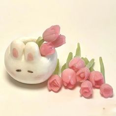 some pink flowers are in a white vase and one is laying on the ground with it's eyes closed