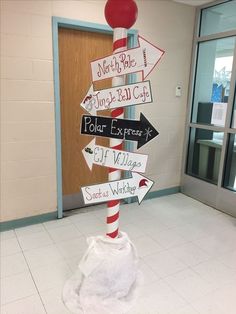 a pole with many different signs on it in the middle of a room next to a door