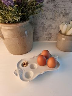 three eggs in an egg tray on a table next to some lavenders and flowers