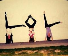 three women doing handstands in front of a wall