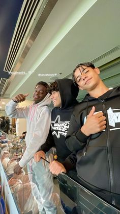 three young men standing next to each other in front of a display case at an airport