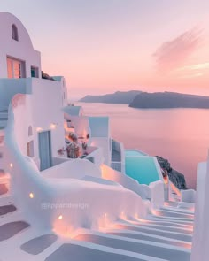 the sun is setting over an ocean and some buildings with lights on them in oia, greece