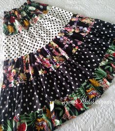 a black and white polka dot skirt with flowers on the bottom, sitting on top of a bed