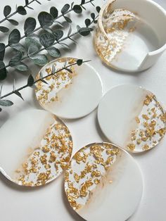 four white and gold plates sitting on top of a table next to a green plant