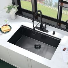 a kitchen sink sitting under a window next to a counter top with a plate of food on it