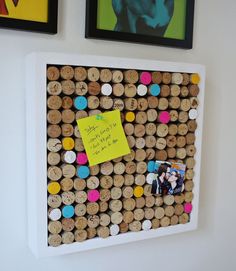 a cork bulletin board with pictures on the wall behind it and a note pinned to one of the corks