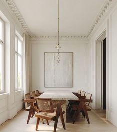 an empty dining room with white walls and wooden chairs around a large table in the center