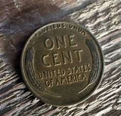 a one cent coin sitting on top of a piece of wood with the words, one cent united states of america