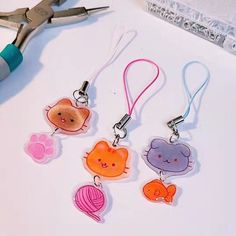 four keychains with different designs on them sitting next to some scissors and thread