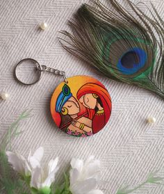 a keychain with an image of two people on it next to a peacock feather