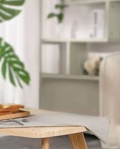 a wooden table with bread on it in front of a white couch and potted plant