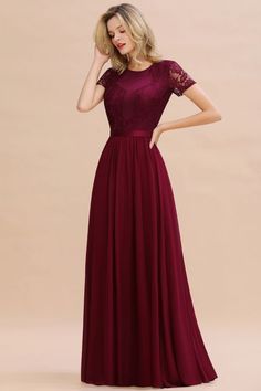 a woman wearing a long burgundy dress with sheer sleeves and lace detailing on the shoulders