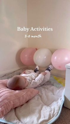 a baby laying on top of a bed next to pink and white balloons with the words baby activities 3 - 6 months