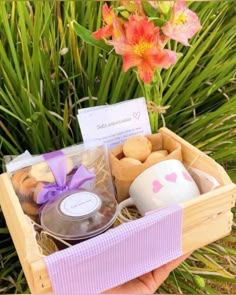 a person holding a wooden box filled with different types of treats and teas in front of some flowers