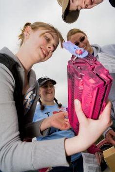 a group of people standing around each other holding a pink object in front of them