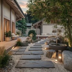 a stone path leading to a house with lights on the side and trees in the back