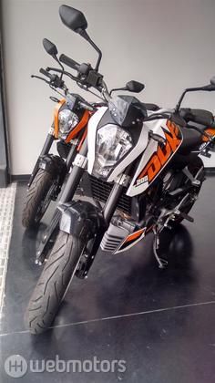 an orange and white motorcycle is parked in a room with tile flooring on the walls