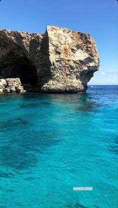 the water is crystal blue and there are some cliffs in the background that look like they have been built into the rocks