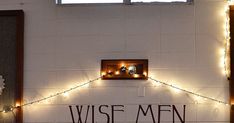 a white wall with some lights on it and the words wise men written in black