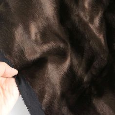 a person is holding something in their hand while wearing a black coat with fur on it