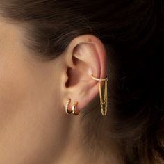 a close up of a woman's ear with two gold chains attached to it