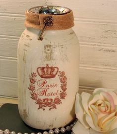 a white jar sitting on top of a table next to a flower and pearls necklace