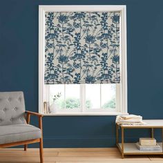 a living room with blue walls and a window covered in roman blind shades that have flowers on them