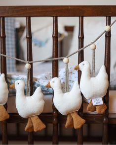 five stuffed ducks hanging from a rope in a crib