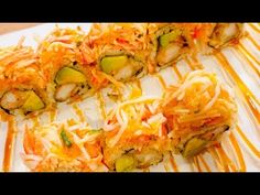 sushi rolls covered in cheese and vegetables on a white plate