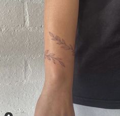 a woman's arm with a tattoo on it that has an olive branch on it