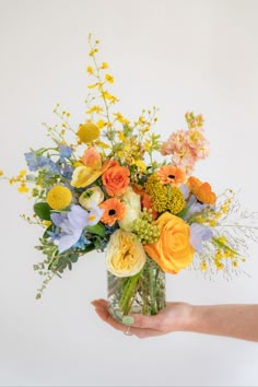 hand holding orange yellow and blue floral arrangement in a glass container in front of a white background. Orange Yellow Weddings, Sunny Field, Yellow Flower Arrangements, Blue Flower Arrangements, Orange Bouquets, Giving Flowers, Yellow Bouquets, Yellow Wedding Flowers, Best Flowers