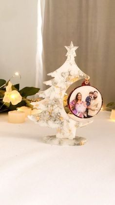 a white christmas tree ornament sitting on top of a table next to candles