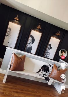 a white bench with brown pillows and pictures on the wall