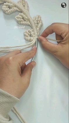 two hands are working on a piece of rope