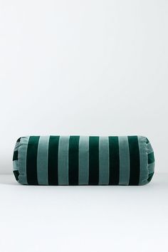 a green and black striped pillow sitting on top of a white floor next to a wall