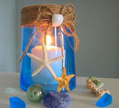 a candle is sitting in a glass jar with starfish on the top and other items around it