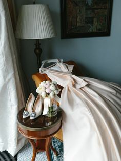 a pair of high heeled shoes sitting on top of a table next to a lamp