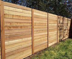 a wooden fence next to a yard with a swing set