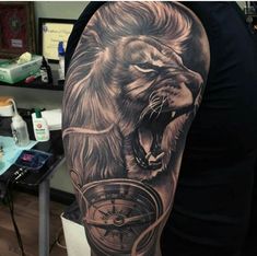 a man's arm with a lion and compass tattoo design on it, in black and grey