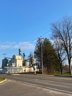 an old factory building sitting on the side of a road in front of some trees