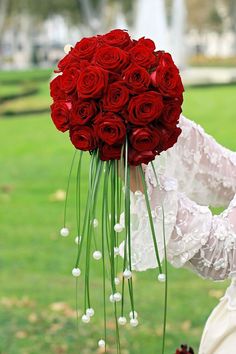 a woman holding a bouquet of red roses